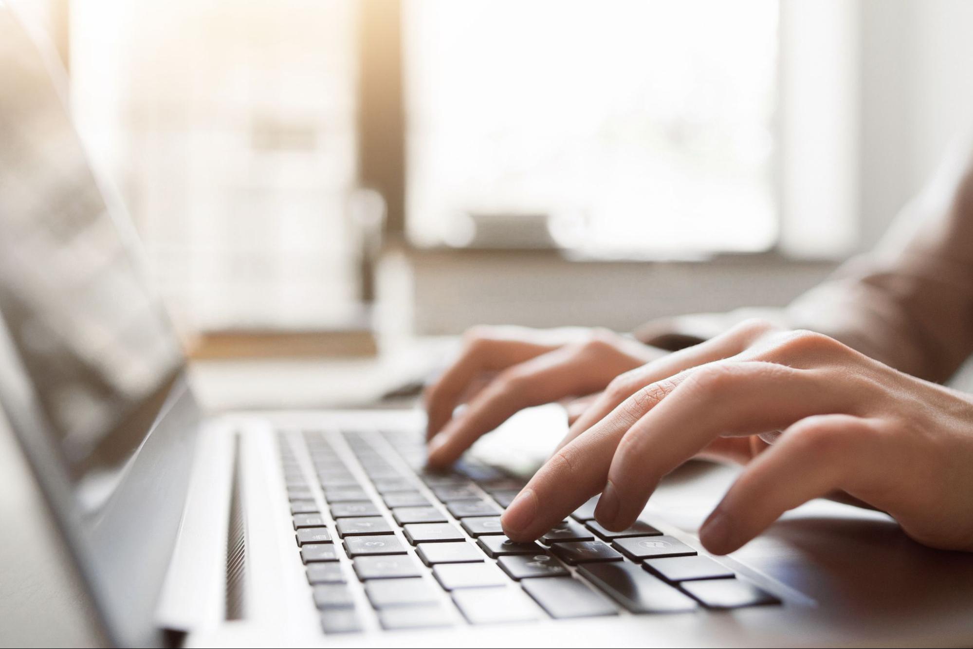 A close up of someone typing on a laptop
