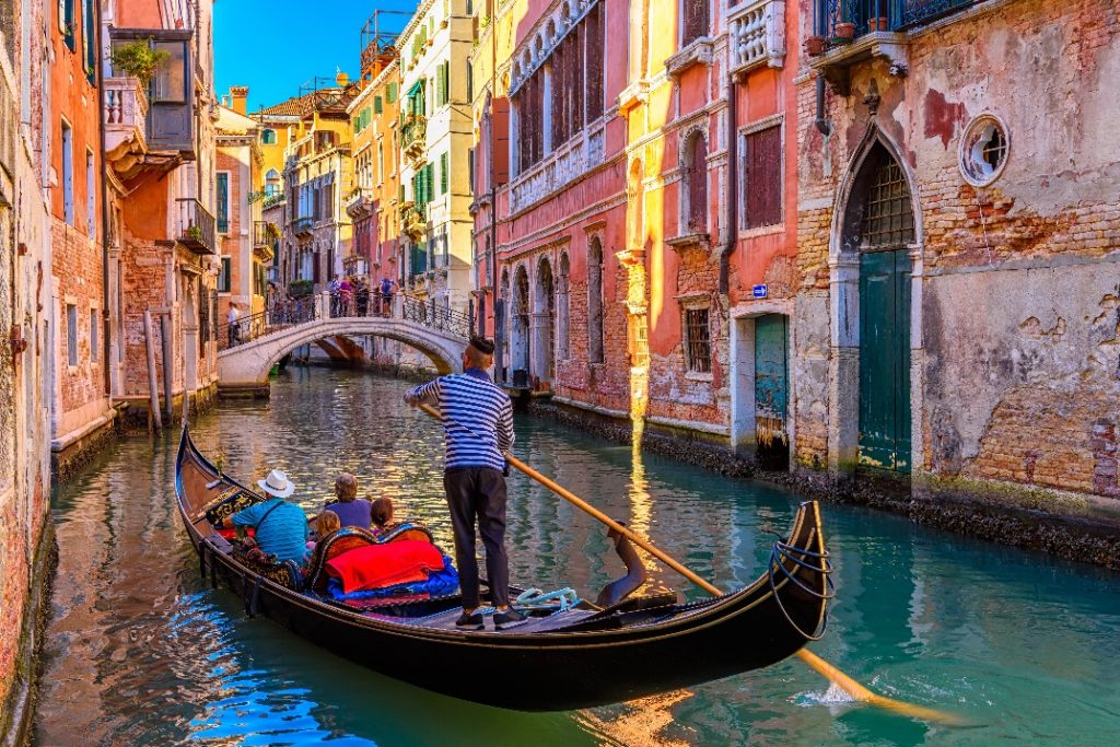 Canal estreito com gôndola e ponte em Veneza, Itália
