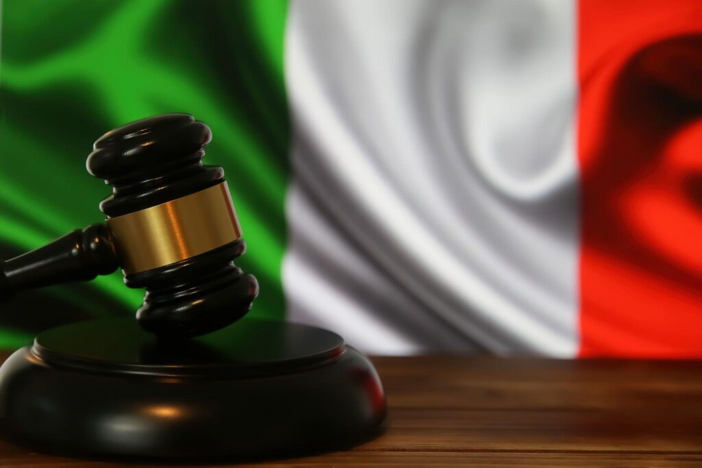 Closeup of isolated judge wood gavel with blurred italy flag background