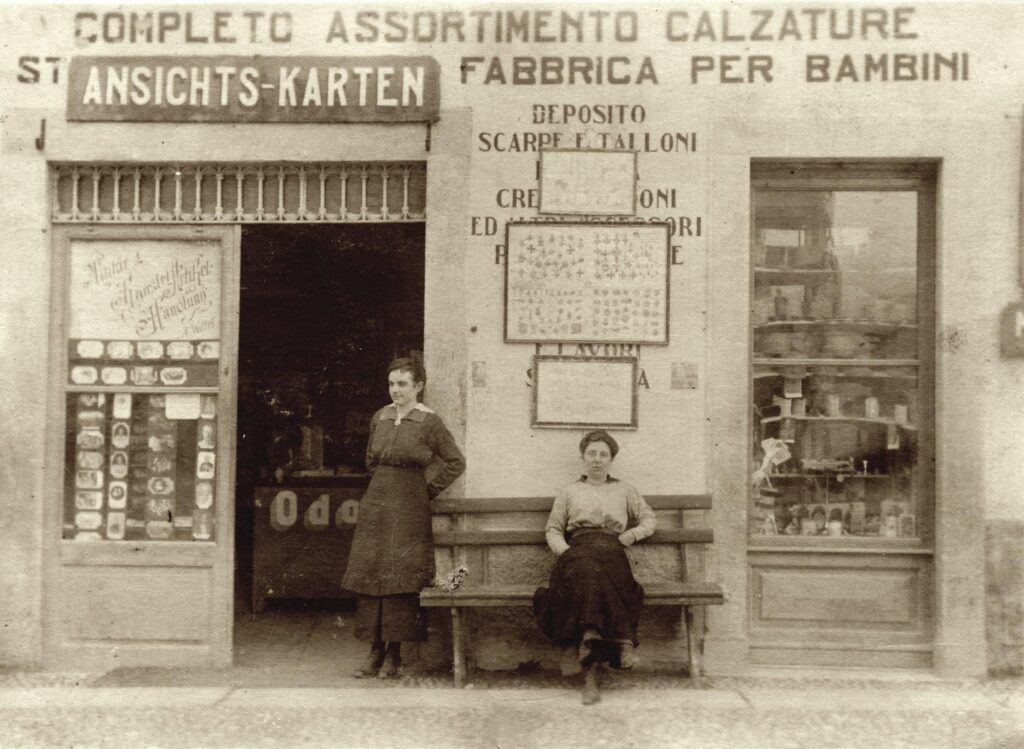 Antique photo with two women posing in front of a shop