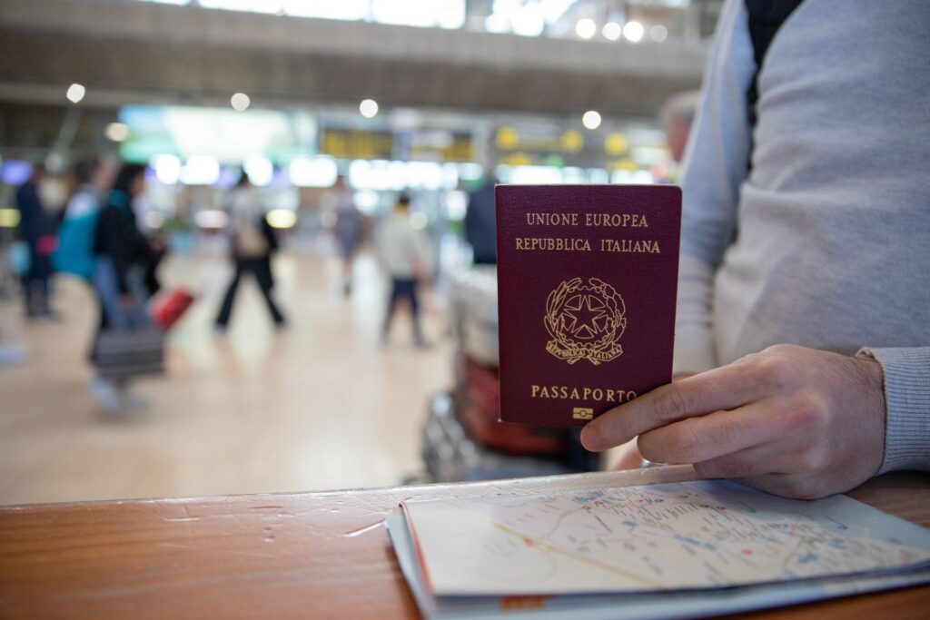 Primer plano de un pasaporte italiano en manos de un viajero con un mapa al lado