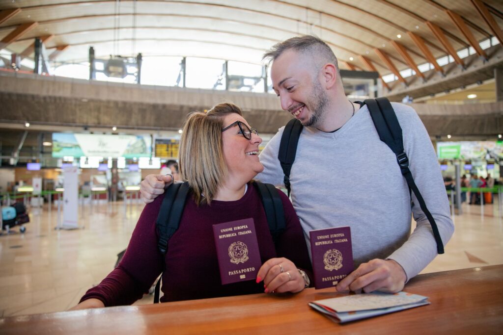 Dois turistas italianos com passaportes na mão no aeroporto olham um para o outro