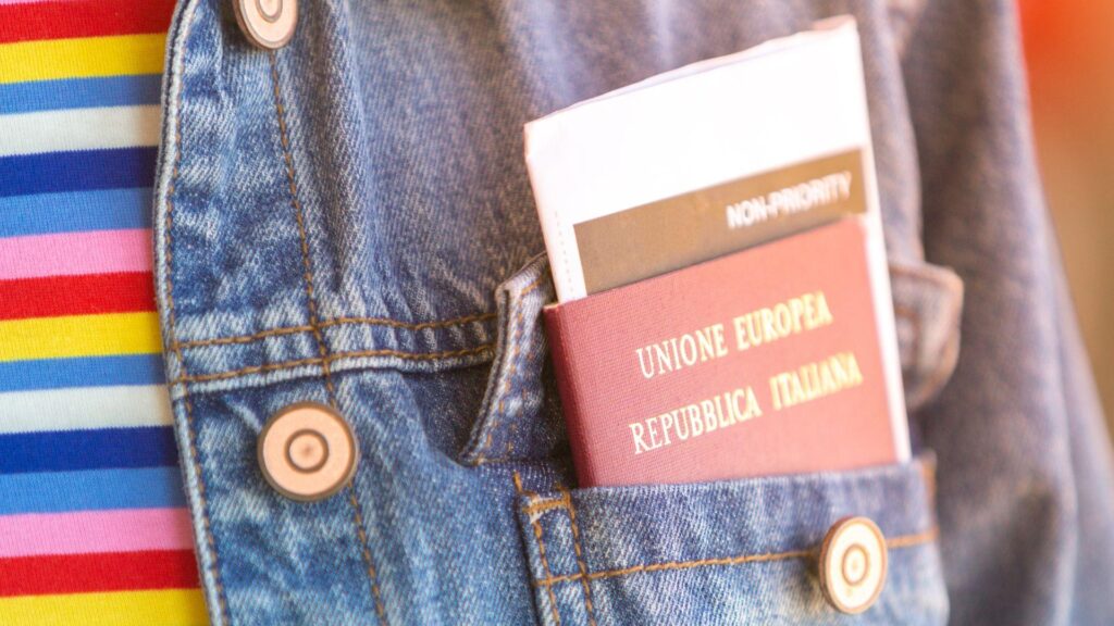 Passaporte italiano e cartão de embarque no bolso da frente do casaco de ganga - mulher a aguardar a partida do voo na sala de espera