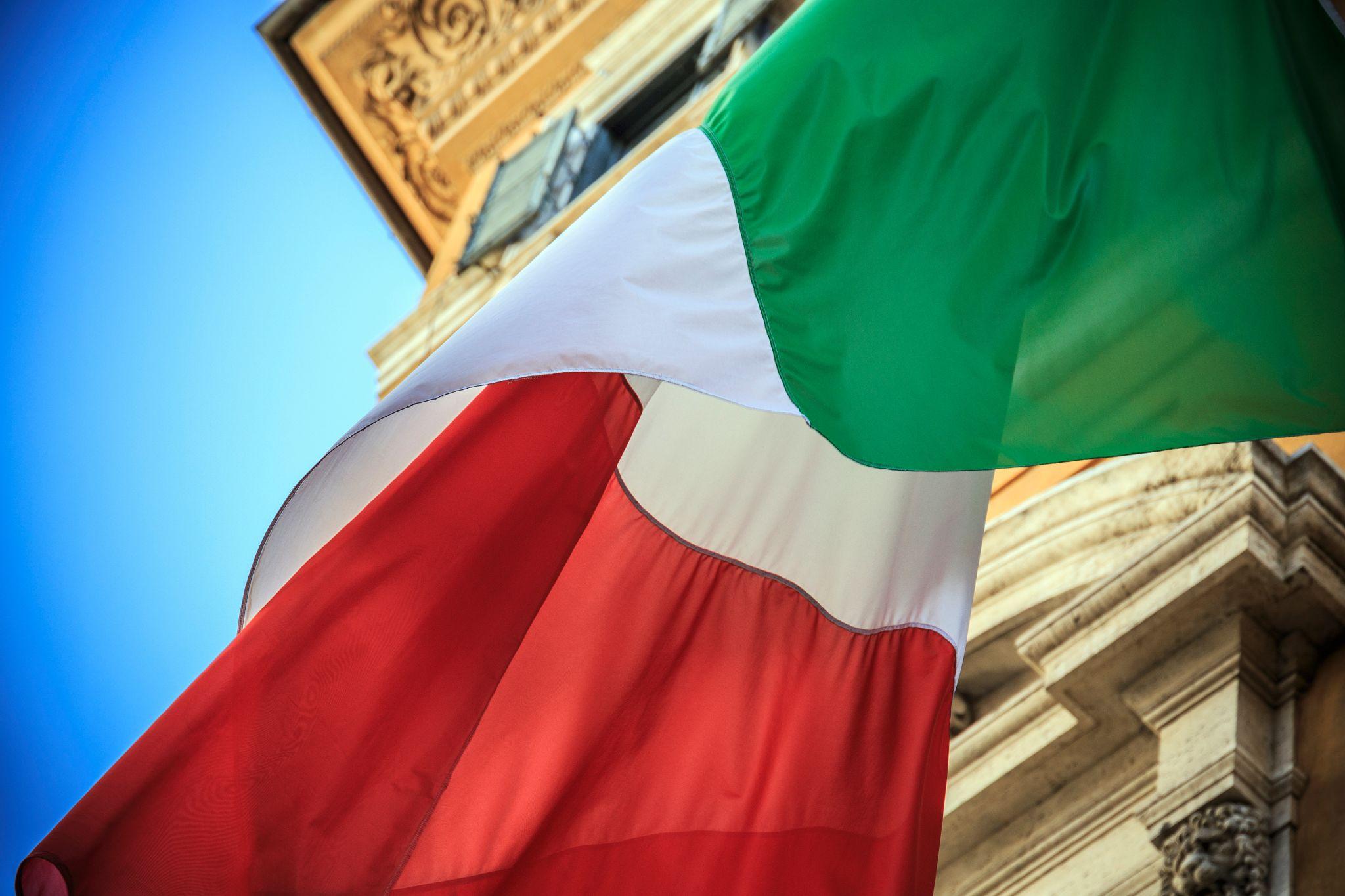 An Italian flag with a historic building in the background
