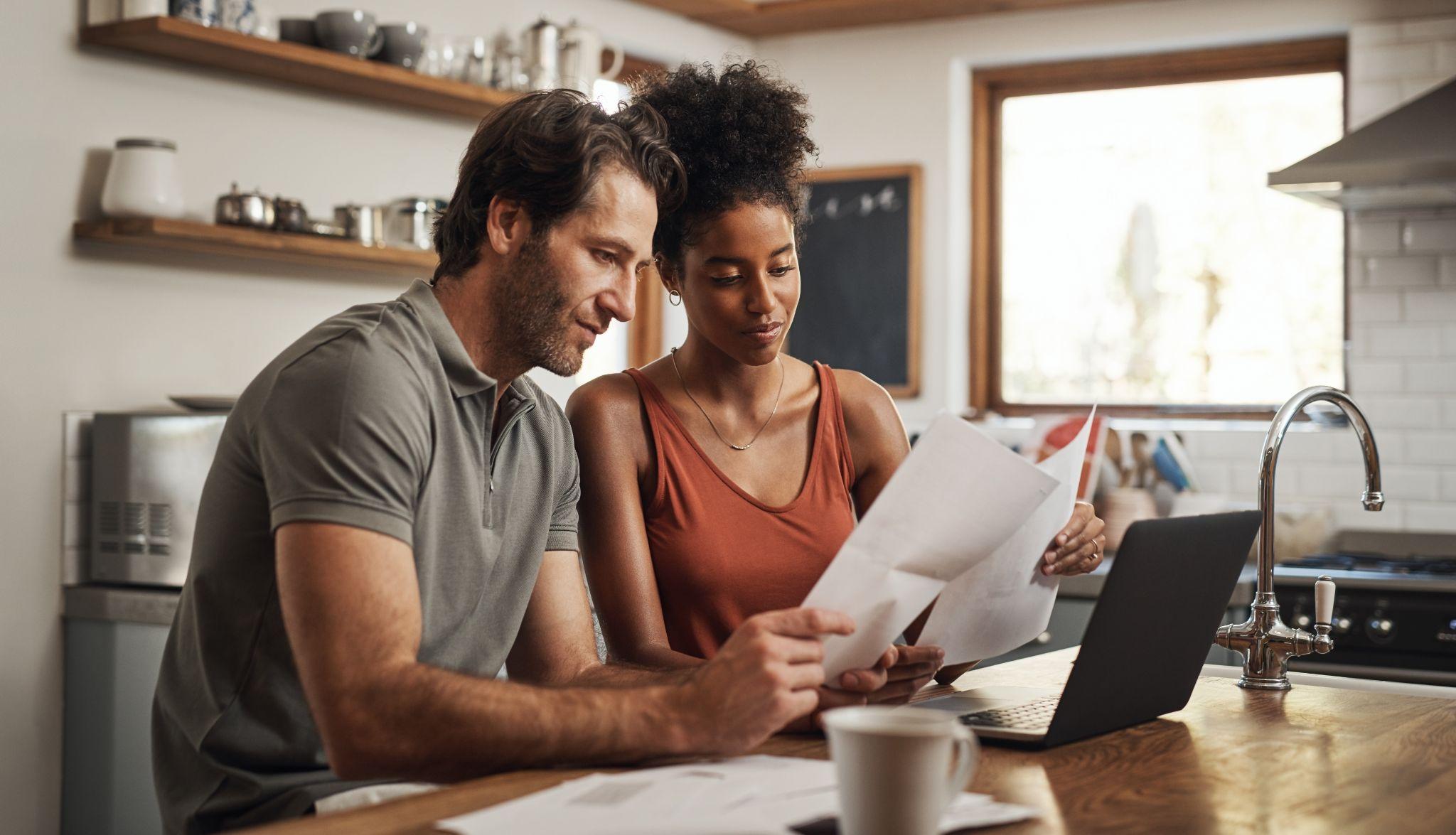 Couple using their laptop and going through paperwork at home