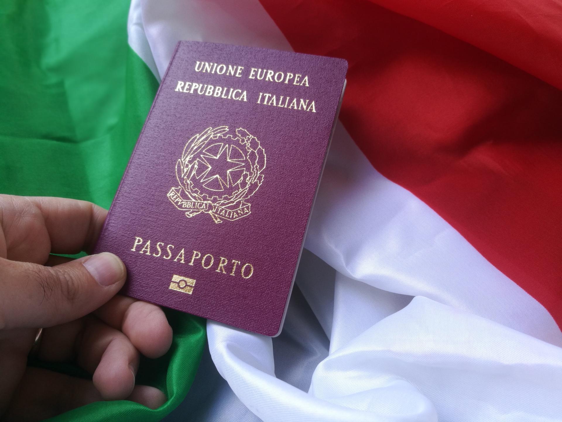 Man's hand holding an Italian Passport