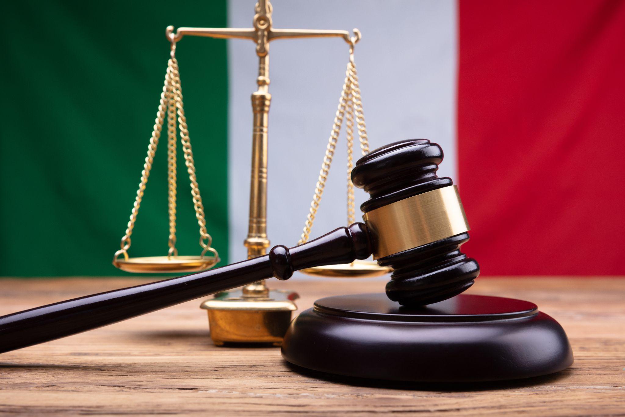 A gavel and scales in front of an Italian flag