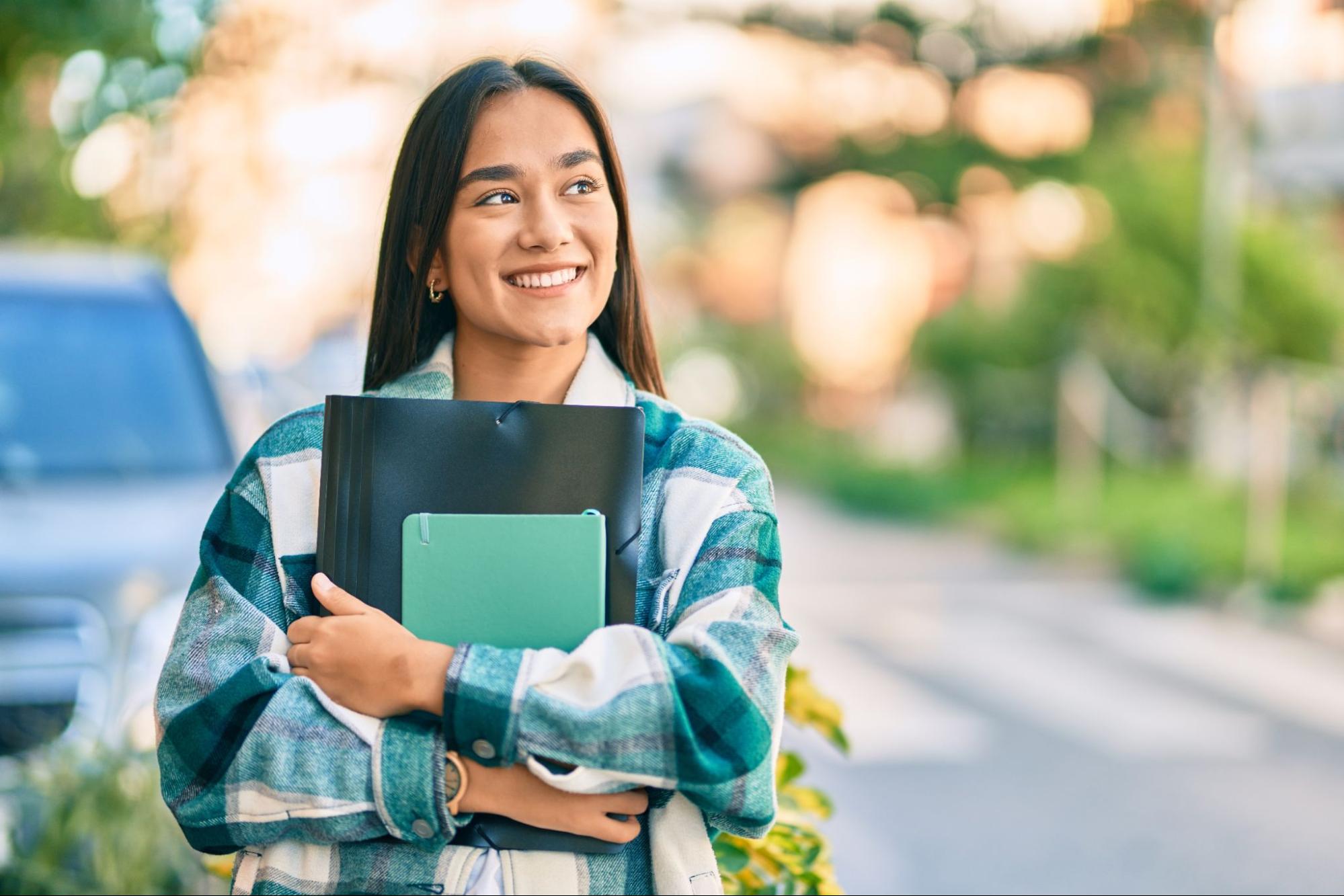 A college student holding notebooks smiling