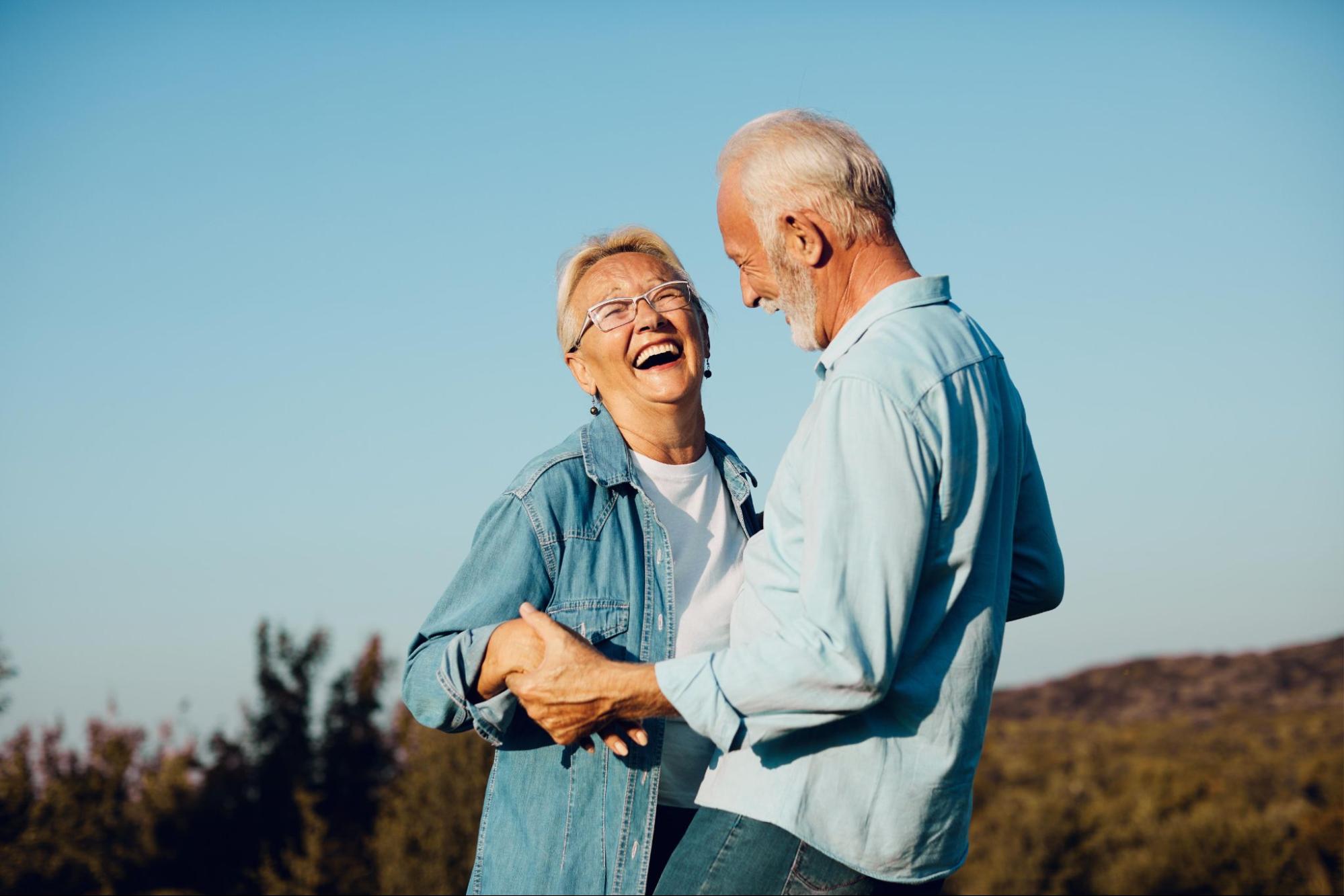 An older couple smiling and laughing outside