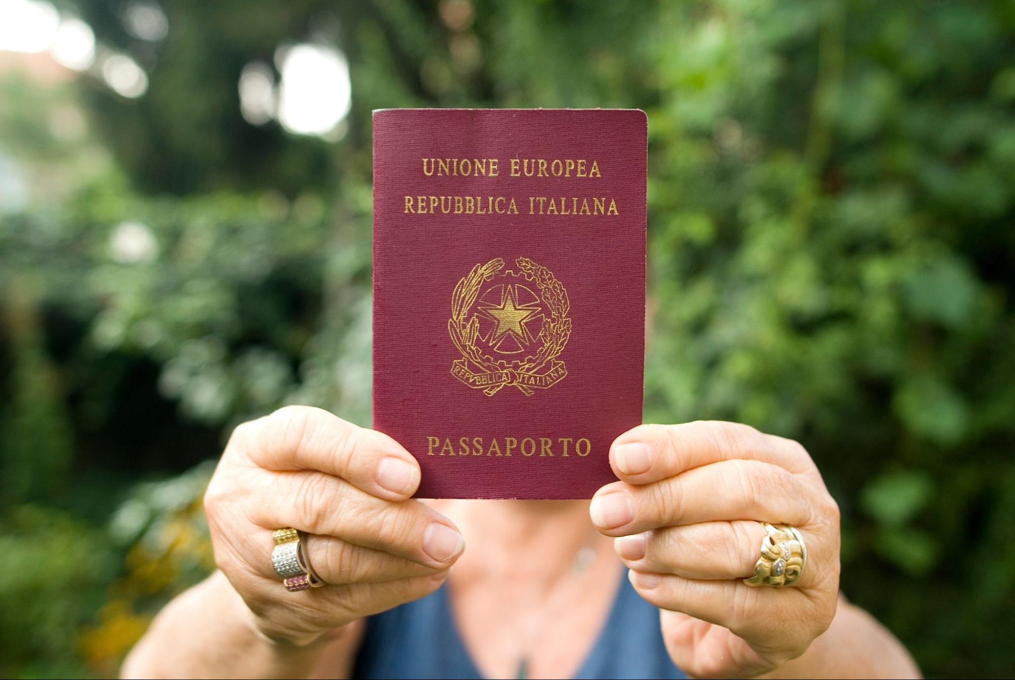 Uma mulher mostrando seu passaporte italiano para a câmera