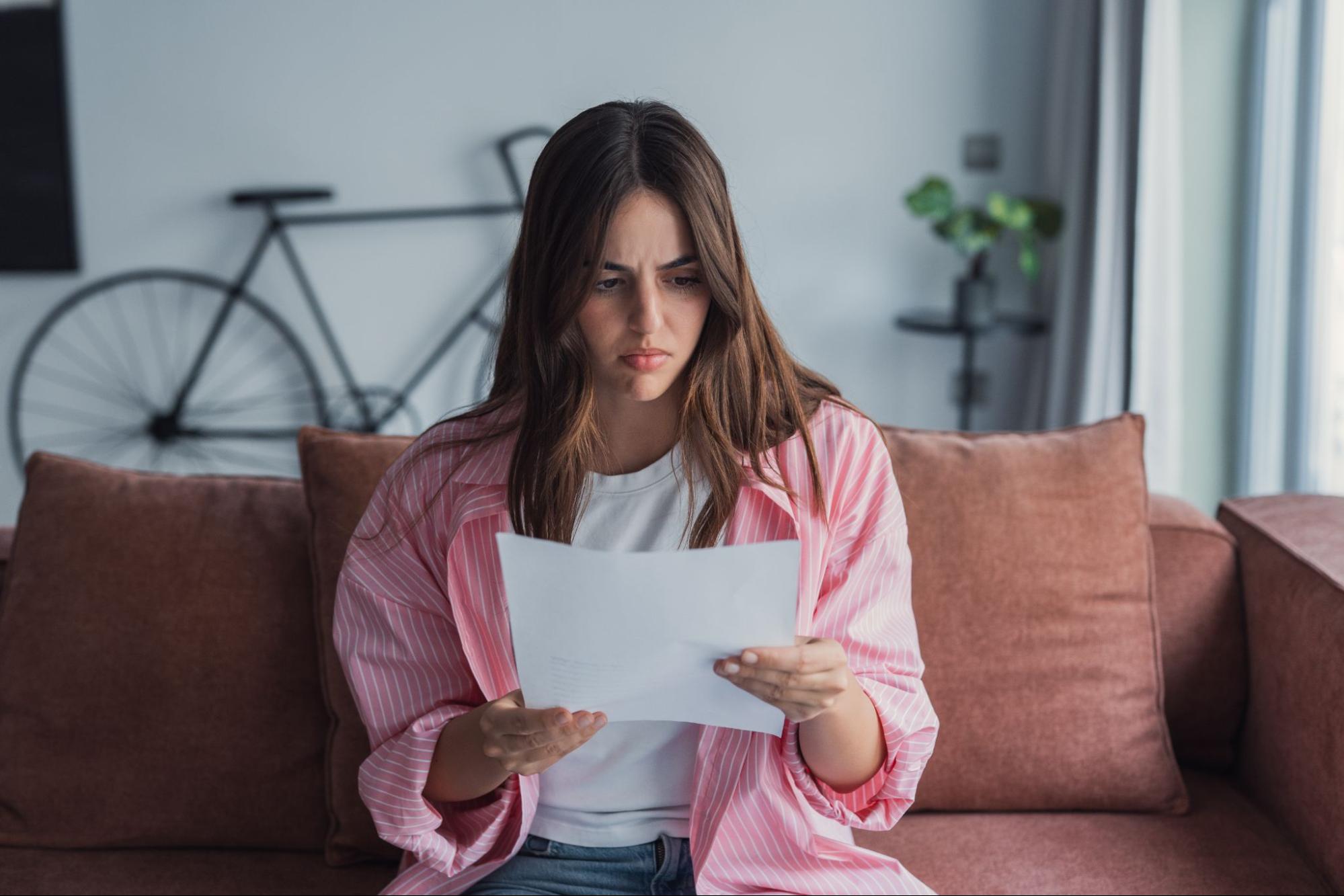 Uma mulher lendo uma carta com uma expressão preocupada no rosto